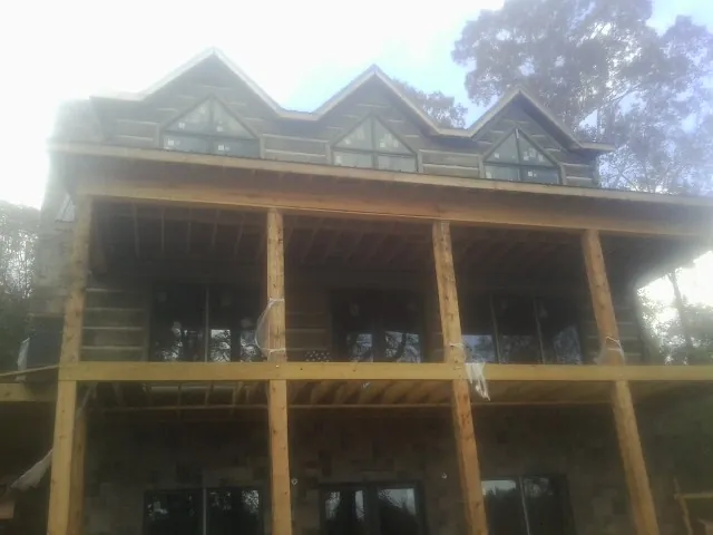 Dormers and porch framing on a large log home under construction — Roof Coating work by our crew in Williston