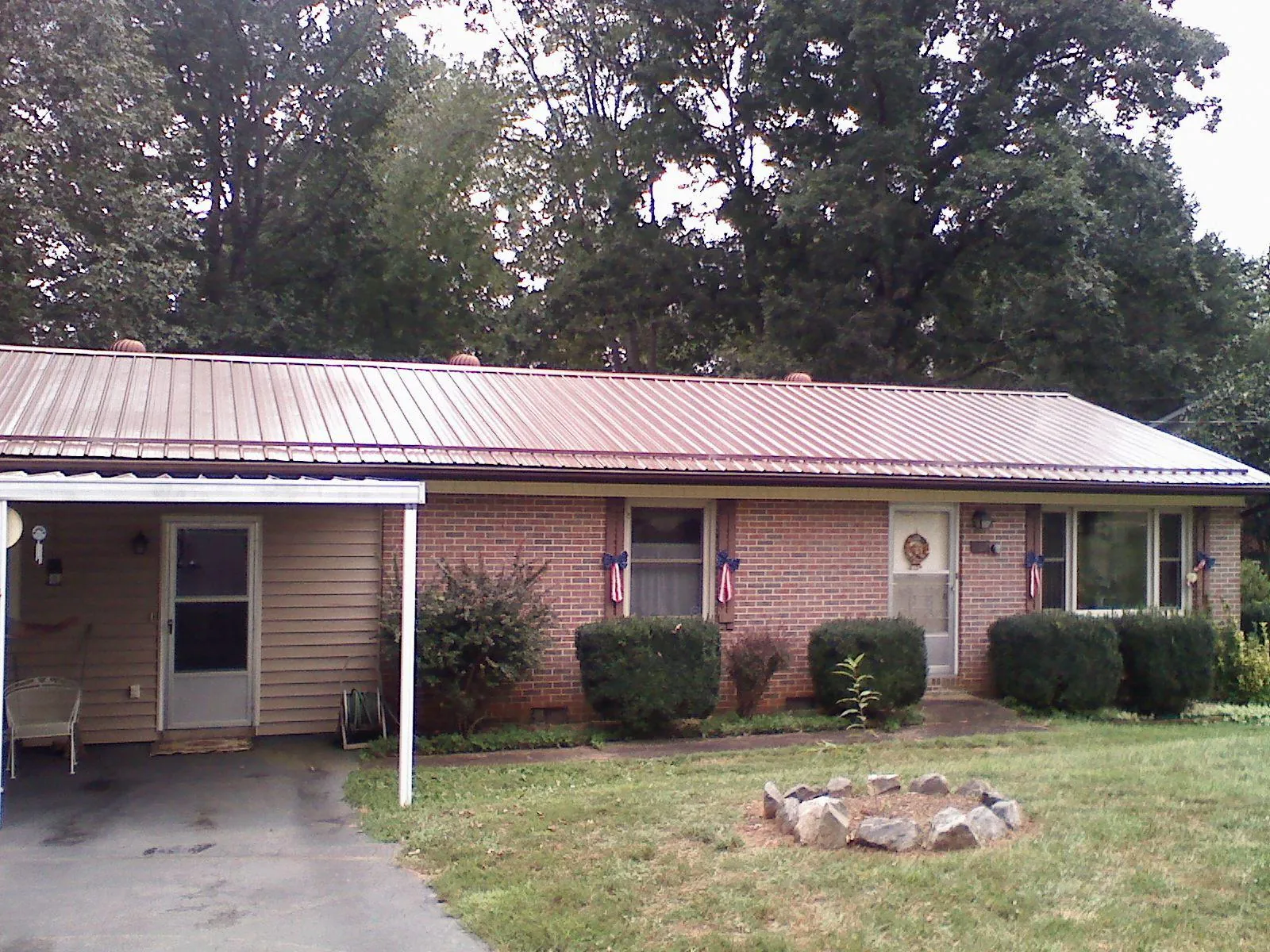 Bronze metal roof and carport on a brick ranch home — Roof Repair work by our crew in Williston