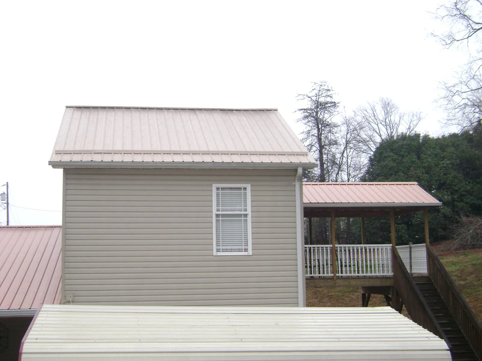 Tan metal roofs on a two story addition and attached porch, from a Roof Replacement job in Williston